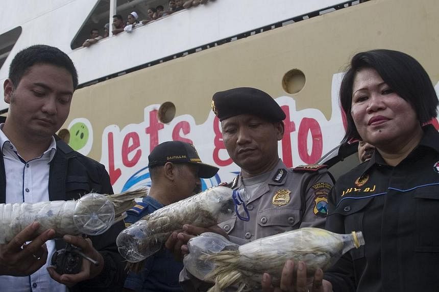 Indonesian police and customs officials hold rare Indonesian yellow-crested cockatoos placed inside water bottles confiscated from alleged wildlife smuggler. -- PHOTO: REUTERS