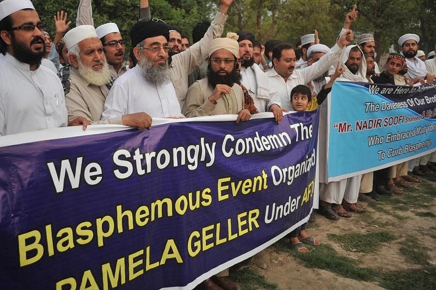Pakistani residents shout slogans as they march behind a banner during a protest in Peshawar on Tuesday, against the anti-Muslim cartoon exhibition that was attacked by gunmen in Garland, Texas. -- PHOTO: AFP