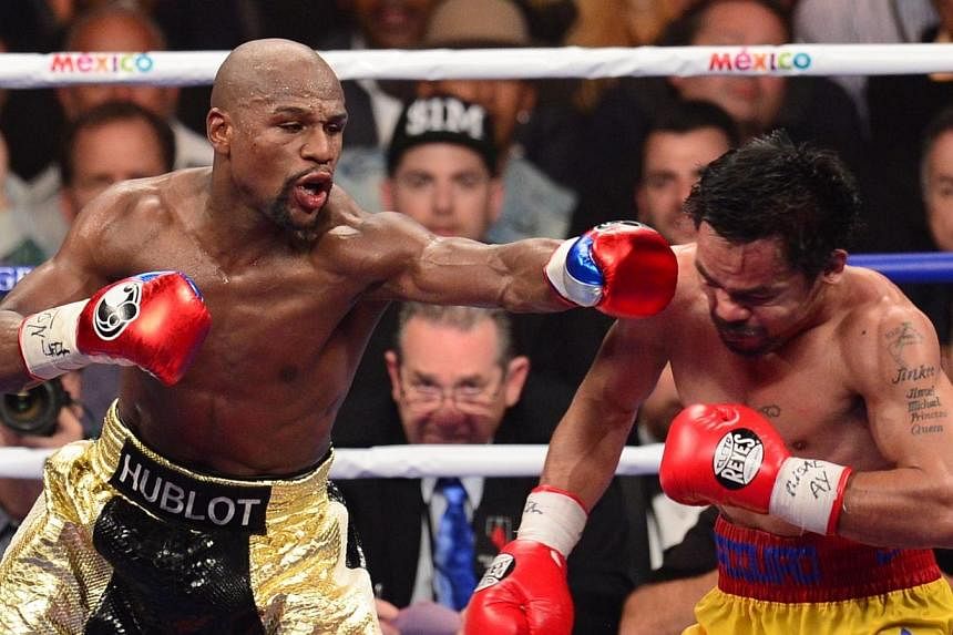 Floyd Mayweather Jr. (left) connects against Manny Pacquiao (right) during their welterweight unification bout on Saturday at the MGM Grand Garden Arena in Las Vegas. Mayweather remains undefeated with a unanimous decision. -- PHOTO: AFP&nbsp;