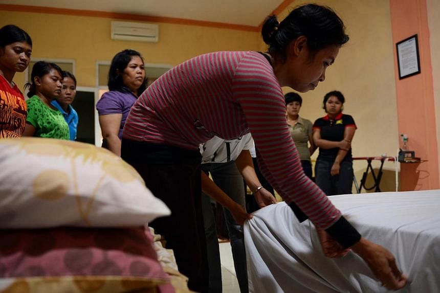 In this file photograph taken on January 27, 2014, an Indonesian maid learns to fix a bed in Jakarta during a class for a group of maids undergoing training at a private recruitment agency deploying maids to foreign countries. -- PHOTO: AFP&nbsp;