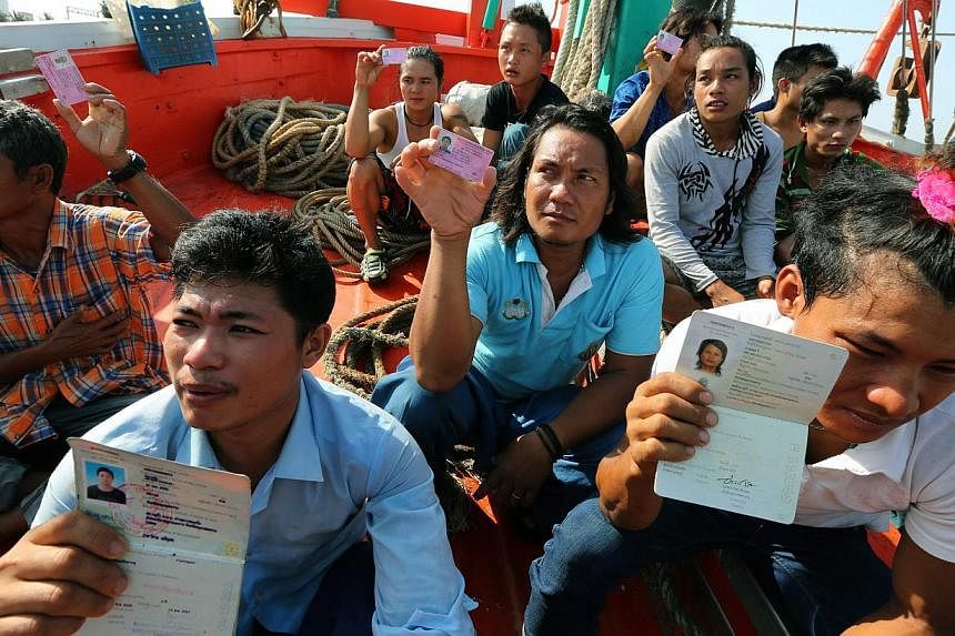 Migrant workers show their migrant worker cards as Thai authorities inspect a fishing boat in Mae Klong district, Samut Songkhram province, Thailand, on May 7, 2015. -- PHOTO: EPA
