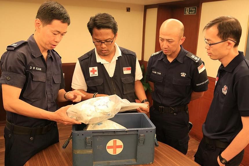 The Singapore Red Cross receiving boxes of medical supplies from the Home Team contingent. Present is (from left) Major (NS) Alex Kuan, Mr Khairulnizam, Lieutenant-Colonel Alvin Tan and Assistant Commissioner Lian Ghim Hua. -- PHOTO: MINISTRY OF HOME