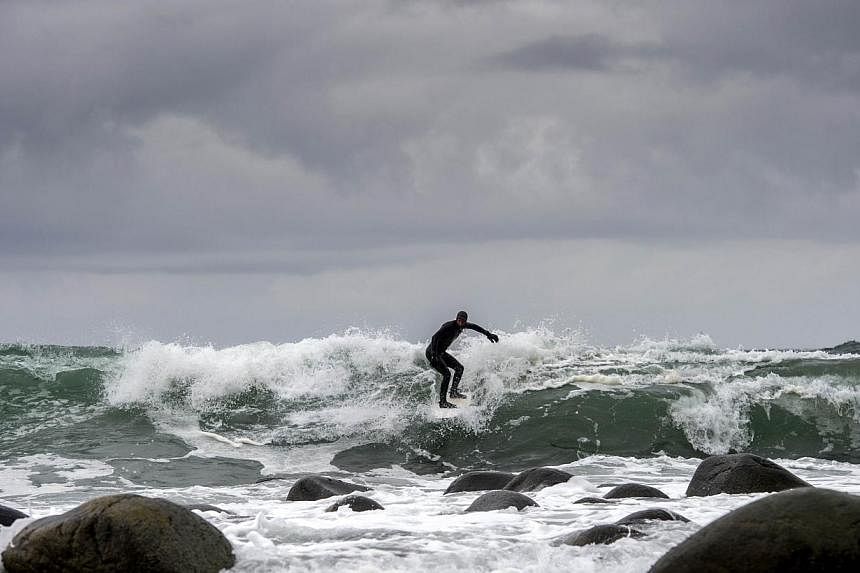 A Swedish tourist surfs last month in Unstad beach in the Lofoten Islands within the Arctic Circle, where carbon dioxide levels rose to record highs in 2012. -- PHOTO: AFP