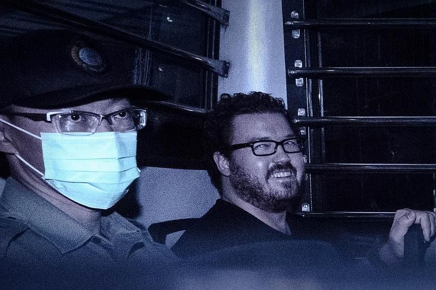British banker Rurik Jutting (right), charged with the grisly murders of two women, smiles as he sits in a prison van leaving the eastern court in Hong Kong on Nov 10, 2014. -- PHOTO: AFP