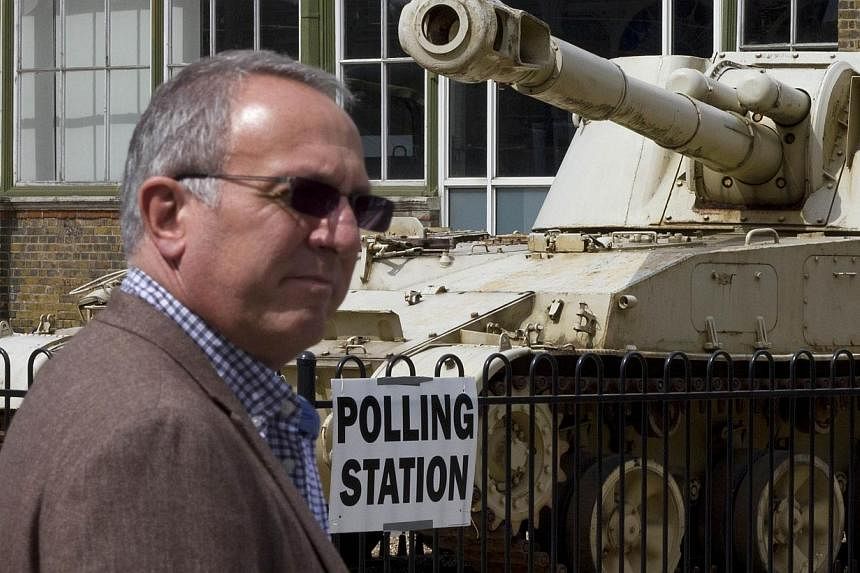 A man passes a 2S3 M-1973 Akatsiya 152-mm self-propelled gun howitzer tank outside the Greenwich Heritage Centre, set up as a polling station in London on Thursday, as Britain holds a general election. -- PHOTO: &nbsp;AFP