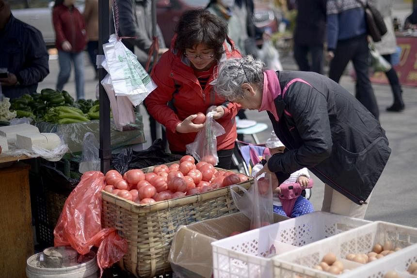 People buying vegetables at an outdoor market in Beijing on April 10, 2015. -- PHOTO: AFP