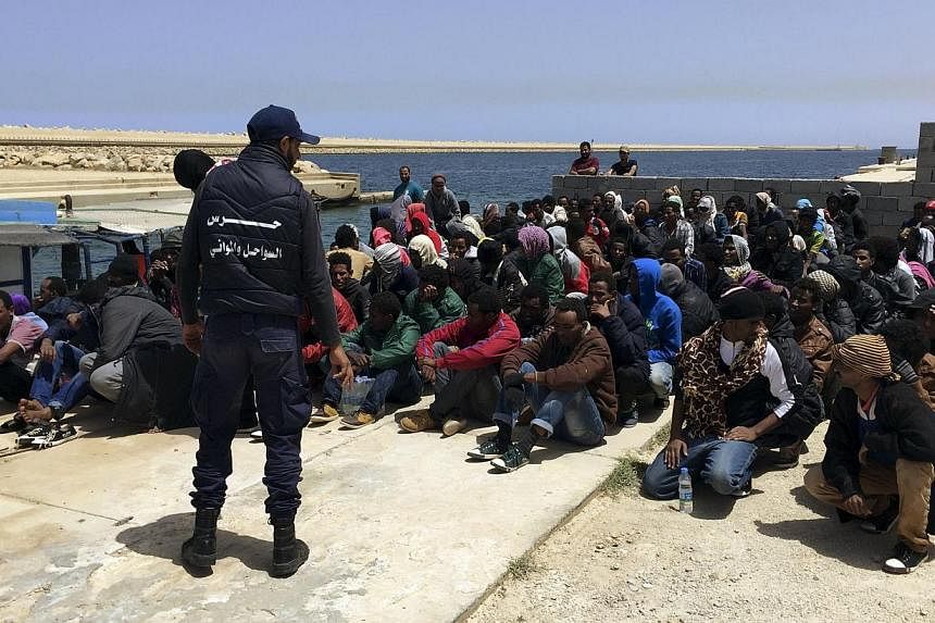 A coast guard (back to camera) stands over illegal migrants who attempted to sail to Europe, on the shore after the migrants' boat was intercepted at sea by the Libyan coast guard, at Khoms, Libya on&nbsp;May 6, 2015. Defence ministers from five Euro