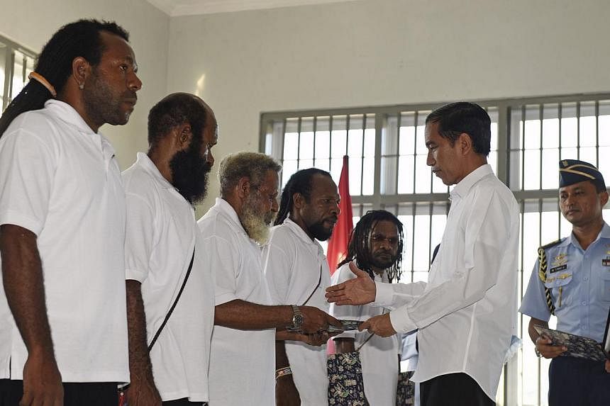Indonesia's President Joko Widodo (right) handing over the official pardon to five political prisoners he granted clemency to, during a ceremony at a prison in Jayapura, Papua province, on May 9, 2015. President Widodo said on Sunday, May 10, that&nb