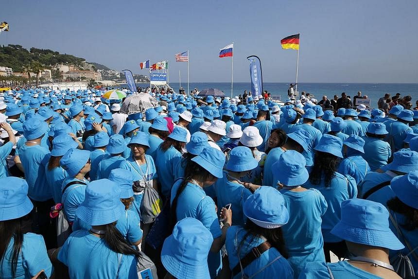 Employees of Chinese company Tiens attend a parade on May 8, 2015 in Nice organised by Tiens chief executive Li Jinyuan as part of a two-day celebration weekend for the 20th anniversary of his company, to which he invited 6,400 of his employees. -- P
