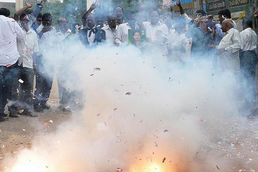 Supporters of All India Anna Dravida Munnetra Kazhagam (AIADMK) supremo, Jayalalithaa Jayaram light fire crackers as they celebrate on hearing the news of the acquital of their leader in the 18-year-old, disproportionate assets case in Bangalore on M