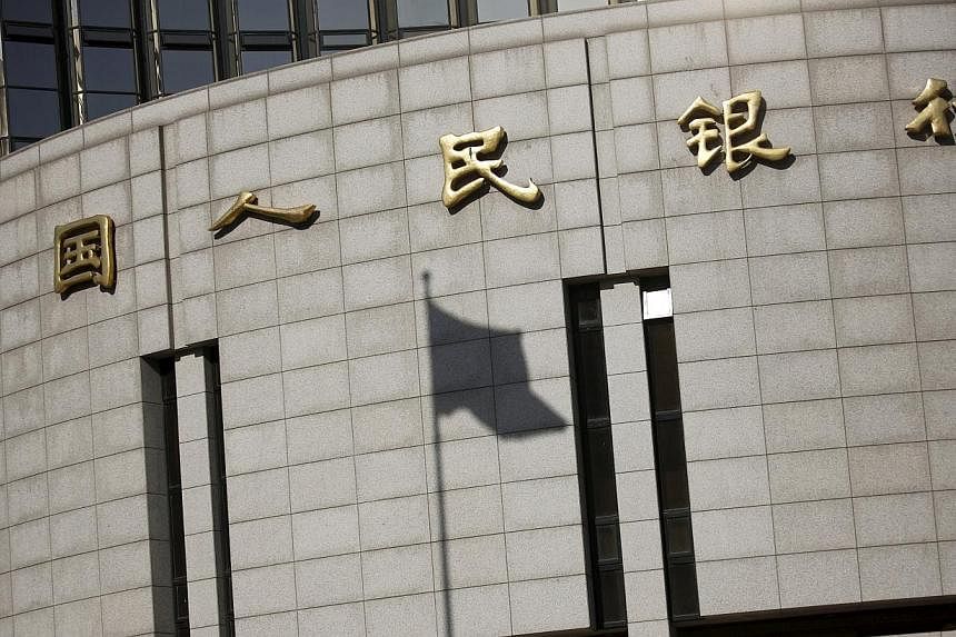 A fluttering Chinese national flag casts its shadow on the headquarters of the People's Bank of China, China's central bank, in central Beijing in this Nov 24, 2014 file photograph. China's central bank cut its benchmark interest rate on May 10, 2015