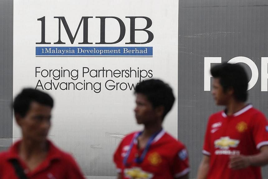 Men walking past a 1 Malaysia Development Berhad (1MDB) billboard at the funds flagship Tun Razak Exchange development in Kuala Lumpur on March 1, 2015. -- PHOTO: REUTERS