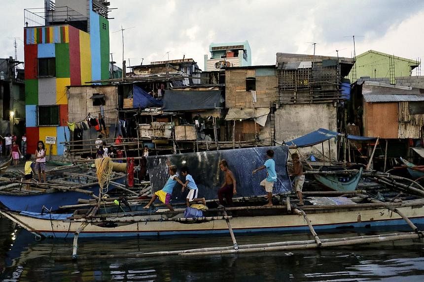 Filipino children walk above an anchored fishing boat in anticipation of typhoon Noul in Navotas city, north of Manila, on May 10, 2015. -- PHOTO: EPA