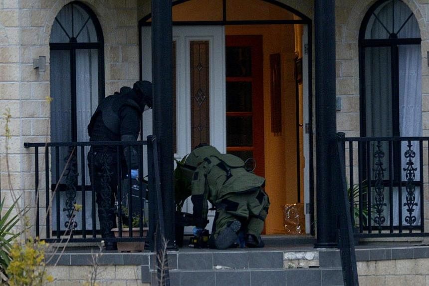 Officers wearing bomb suits raid a home in Greenvale, Melbourne, Australia, on May 8, 2015. An Australian teenager, who was arrested during the raid, has been charged with involvement in a "well advanced terrorist bomb plot and was remanded in custod