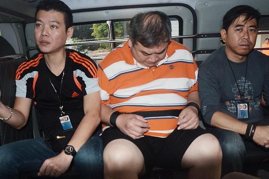 Heng Chen Boon (centre), a credit card promoter, in the police van on Jan 17, 2014. Heng has been charged for the kidnapping of Madam Ng Lye Poh, the mother of Sheng Siong supermarket boss Lim Hock Chee. -- PHOTO: SHIN MIN&nbsp;