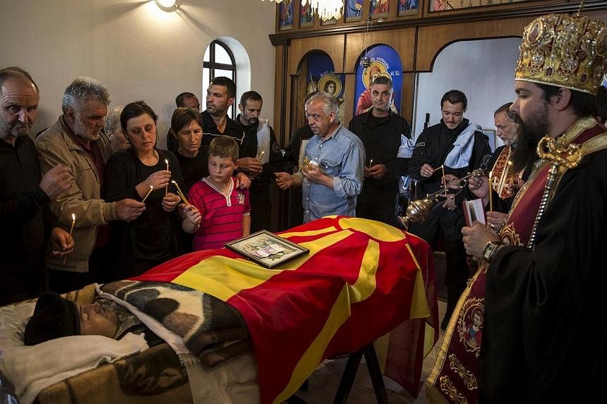 Relatives of &nbsp;policeman Zarko Kuzmanovski mourn next to his coffin draped with the Macedonian flag inside a church during his funeral in the village of Brvenica, Macedonia on Sunday. -- PHOTO: REUTERS