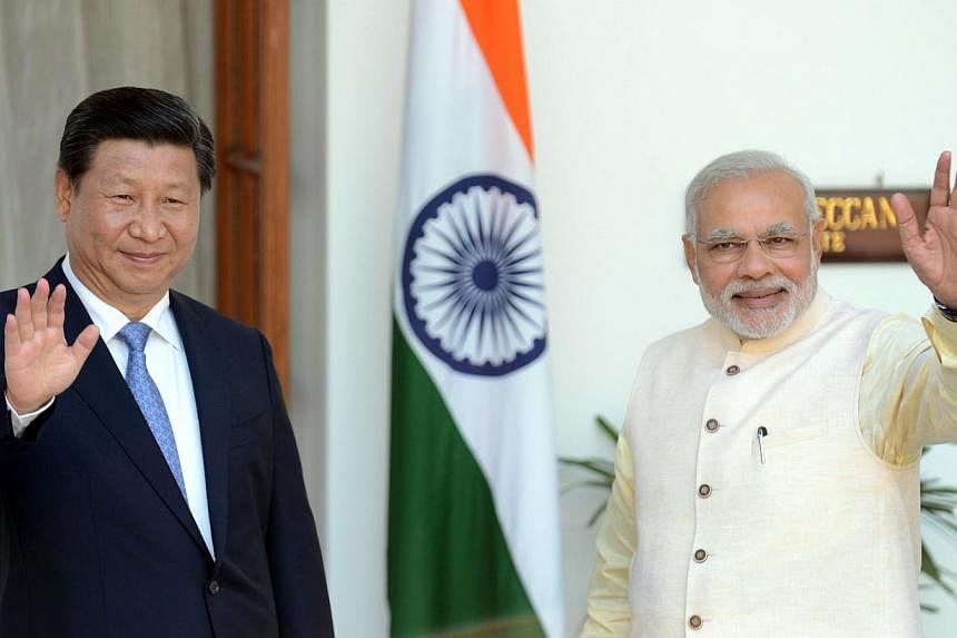 Chinese President Xi Jinping (left) and Indian Prime Minister Narendra Modi waving before delegation talks in New Delhi, in this Sept 18, 2014 photo. Mr Modi will take his global investment push to China this week, as Asia's rival superpowers look to