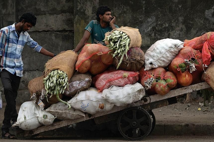 An Indian vendor waits alonside his cart filled with vegetables at the wholesale market in Mumbai on Feb 28, 2015.&nbsp;&nbsp;India's inflation rate fell to its lowest level in four months and growth in industrial output slowed, official data showed 