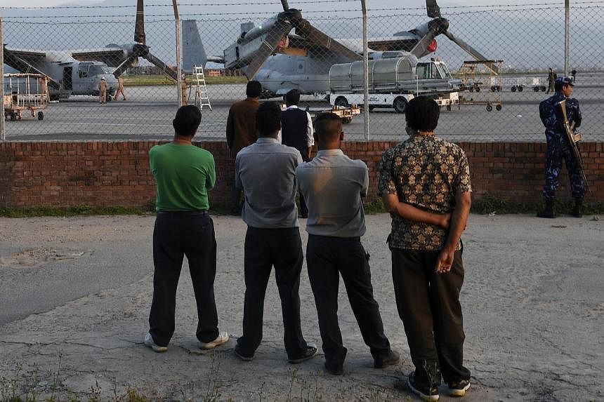 Nepalese men watching US military Osprey aircraft after they landed at Kathmandu's international airport on May 3, 2015. Nepalese authorities ordered the closure of Kathmandu airport on Tuesday after a new earthquake killed at least four people and s