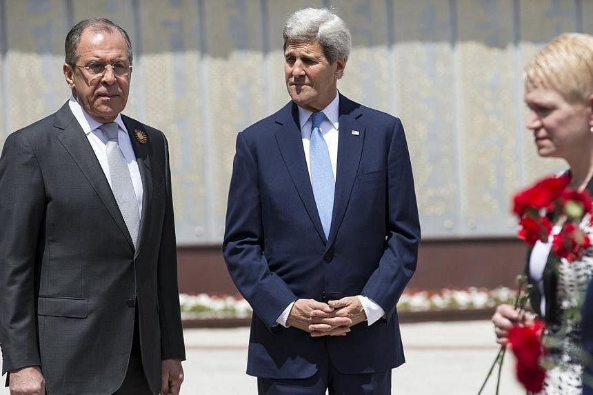 U.S. Secretary of State John Kerry (centre) and Russian Foreign Minister Sergey Lavrov watch as members of the United States and Russian delegations place red flowers at the Zakovkzalny War Memorial in Sochi, Russia May 12, 2015. -- PHOTO: REUTERS&nb