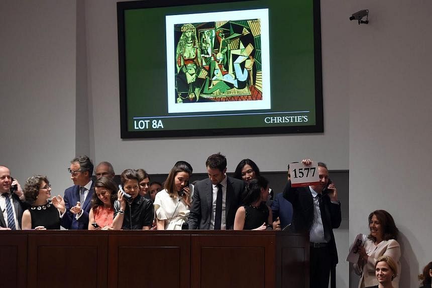 A phone bidder holds up the winning bidder paddle after the Picasso masterpiece "Les Femmes d'Alger (Version O)" sold for USD179.3 million at Christie's in New York City on May 11, 2015, smashing the record for most expensive art sold at auction. -- 