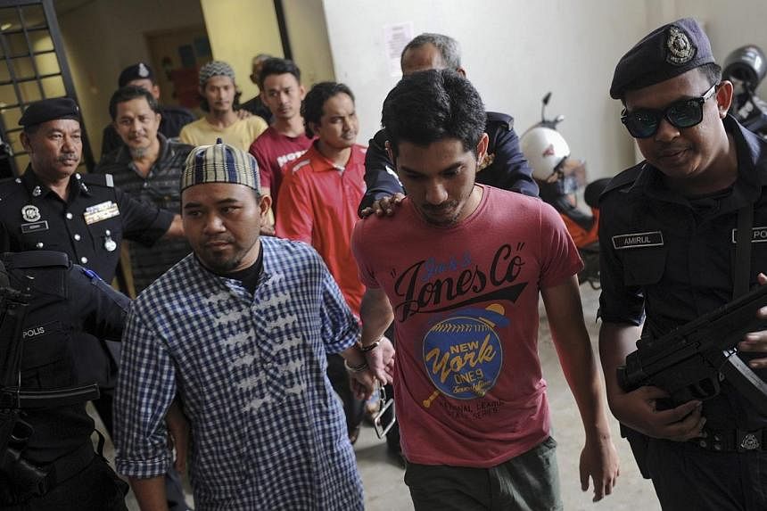 Six suspected ISIS militants (centre), including two Air Force personnel, are escorted by Malaysian Police officers outside the Sessions Court in Alor Star, Kedah, on April 30. They face up to 30 years imprisonment if convicted of promoting acts of t