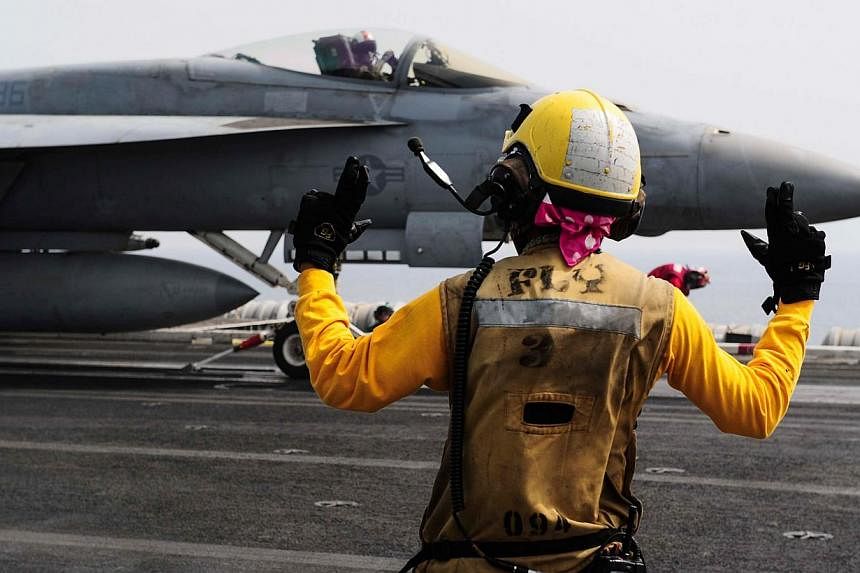 An aircraft handler directs an F/A-18E Super Hornet on the flight deck on board the aircraft carrier USS Theodore Roosevelt (CVN 71) on May 3, 2015. The United States and its allies have conducted 16 air strikes since early on Tuesday, May 12, target