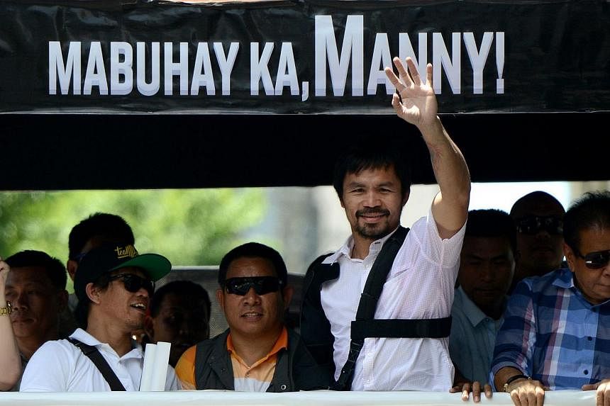 Boxing icon Manny Pacquiao (2nd right) of the Philippines waves to his supporters during a welcome parade in Manila on May 13, 2015. -- PHOTO: AFP