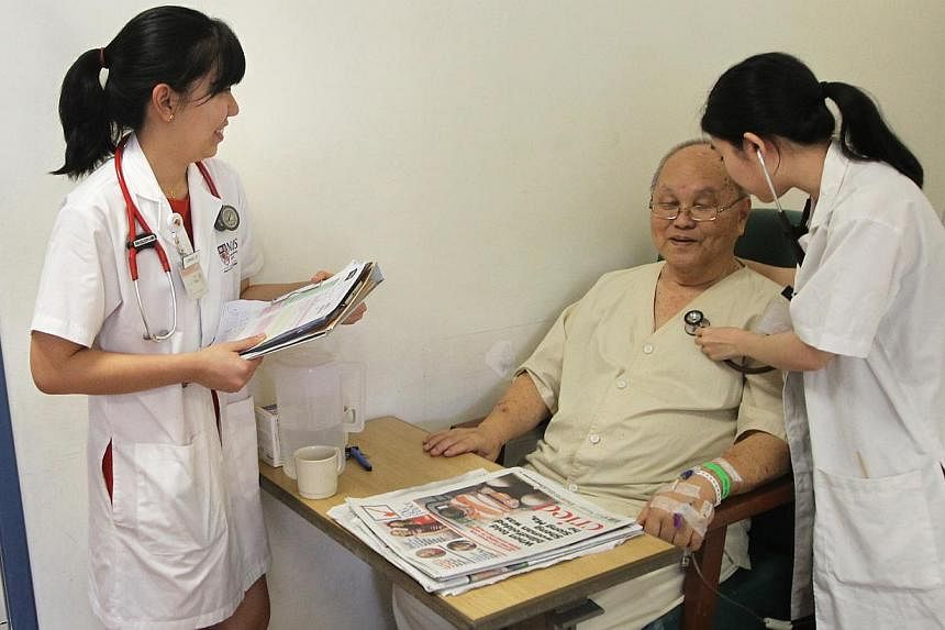 NUS Medicine students Germaine Loo (left) and Alvona Loh with Mr Wee Dick Hoon, 78, a patient at National University Hospital. Eight weeks of their five-year course are devoted to geriatrics.