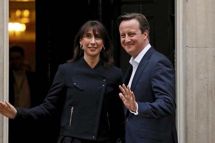 Britain's Prime Minister David Cameron and his wife Samantha wave as they arrive at Number 10 Downing Street in London, Britain on May 8, 2015. -- PHOTO: REUTERS