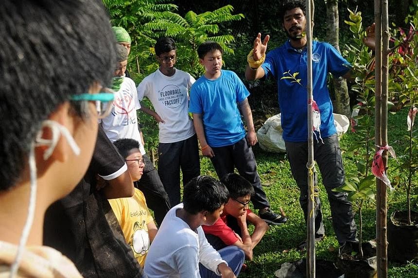 Outward Bound Singapore (OBS) Instructor Shaik Muhammad Iftikhaar (far right), teaching the students the correct way to plant the tree saplings.&nbsp;-- PHOTO:&nbsp;NATIONAL YOUTH COUNCIL &nbsp;