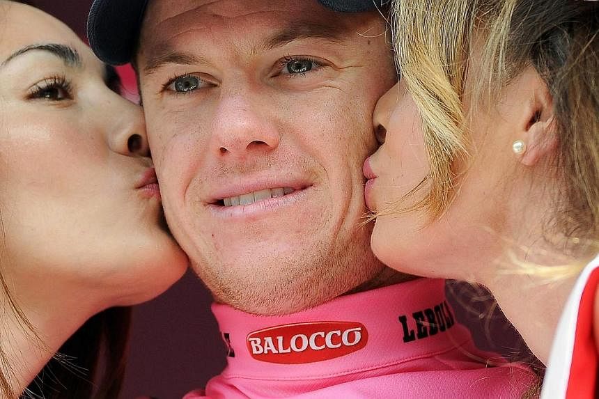 Australian rider Simon Clarke (centre) of the Orica-GreenEdge team is kissed by two hostesses on the podium after taking the overall leader's pink jersey following the fourth stage of the 98th Giro d'Italia cycling tour over 150km from Chiavari to La