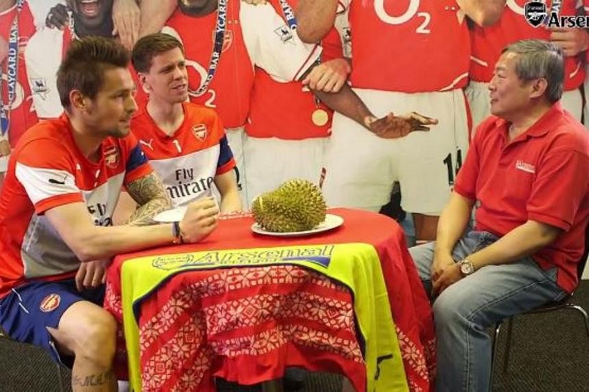 (From left) Arsenal players Mathieu Debuchy and Wojciech Szczesny with Arsenal Singapore's Tiong Jin Yan.&nbsp;-- PHOTO: ARSENAL/FACEBOOK