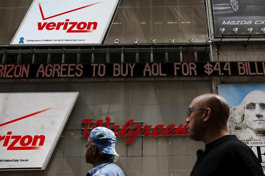 People walk by the Dow Jones electronic ticker at Times Square in New York, May 12, 2015.&nbsp;Wall Street stocks finished lower Wednesday as worries over higher US Treasury bond yields offset Verizon's US$4.4 billion (S$5.8 billion) takeover of AOL.