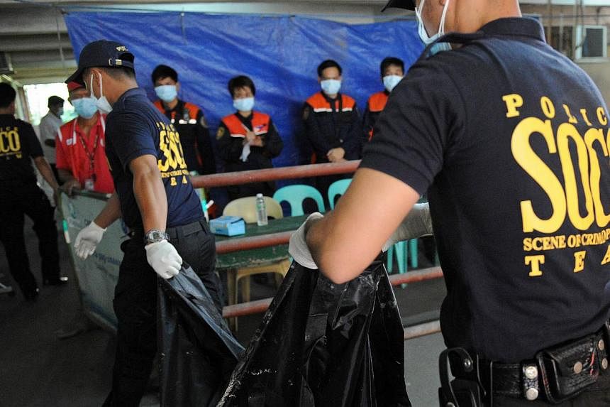 A police forensics team carrying a body bag containing the remains of a victim killed in a fire that gutted a footwear factory in Valenzuela city in suburban Manila on May 14, 2015. -- PHOTO: AFP&nbsp;