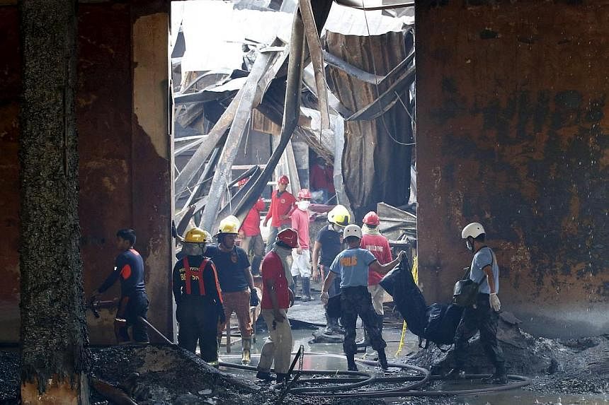 Police carrying a body bag containing a body of a victim as workers remove debris in a gutted slipper factory in Valenzuela, Metro Manila in the Philippines on May 14, 2015. -- PHOTO: REUTERS
