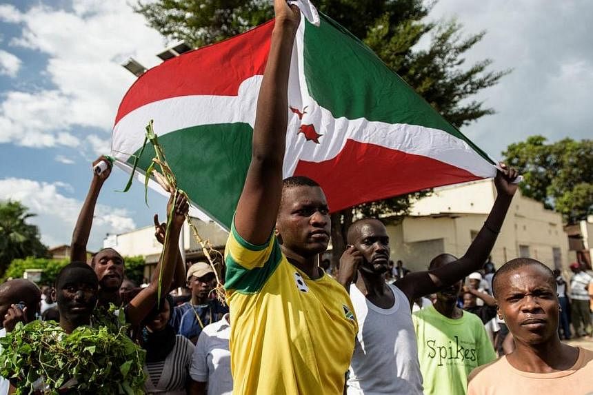 Men hold a Burundi's flag as people take to the streets to celebrate, waving branches, beeping car horns and parading through Bujumbura on May 13, 2015 following the radio announcement by Major General Godefroid Niyombare that President Nkurunziza wa