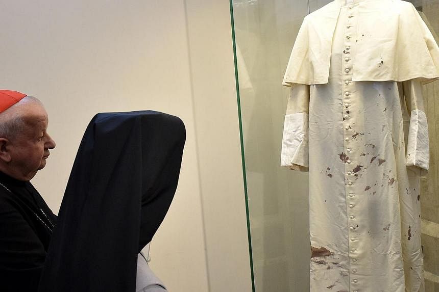 Cardinal Stanislaw Dziwisz (left) and nun Tobiana (second left), who took care of the pope, view the late Pope John Paul II's bloodied cassock in Krakow, Poland, on May 13, 2015. -- PHOTO: AFP&nbsp;