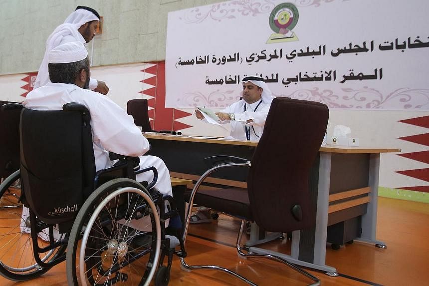 A Qatari man casts his vote for municipal elections at a polling station in Doha, on May 13, 2015. Two women were voted onto the emirate's only directly elected body, the Central Municipal Council, officials announced on Thursday, May 14, a first for