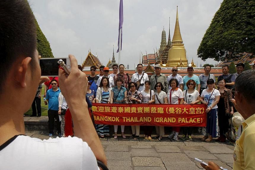 Chinese tourists pose for photos as they visit Wat Phra Kaeo (Emerald Buddha Temple) in Bangkok on March 23, 2015.&nbsp;A Chinese company is sending more than 12,000 people on a holiday to Thailand, tourism officials said Thursday, with one resort ho