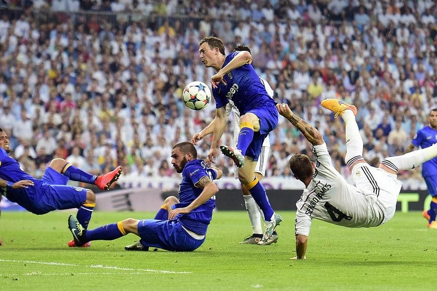 Real Madrid defender Sergio Ramos (right) kicks the ball past Juventus defenders Leonardo Bonucci (second left) and Stephan Lichtsteiner (second right) and midfielder Arturo Vidal during the Champions League semi-final on May 13, 2015. -- PHOTO: AFP&