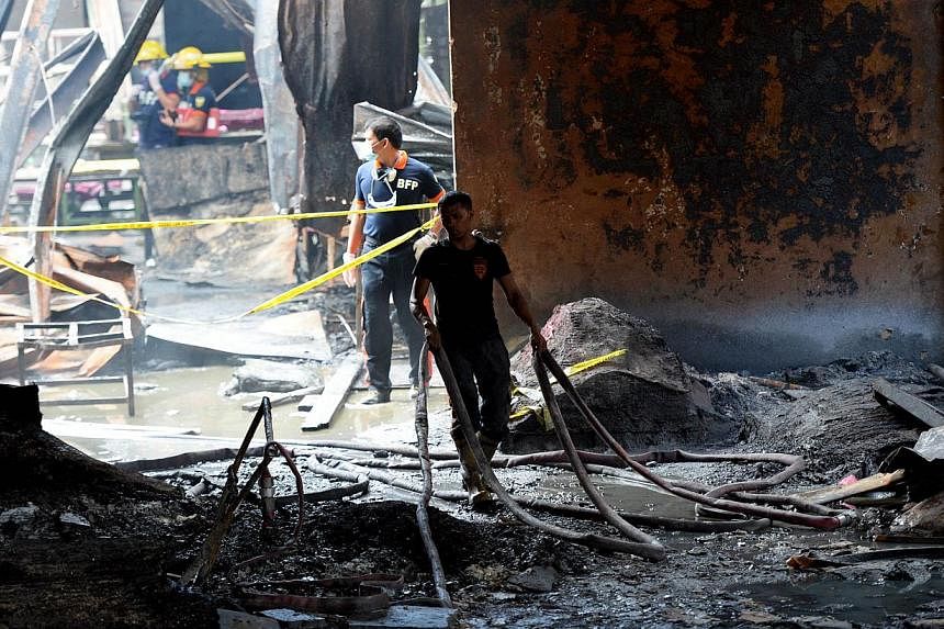 Fire investigators looking for evidence amongst the ruins of a footwear factory in suburban Manila on May 14, 2015, a day after the it was gutted by fire. -- PHOTO: AFP