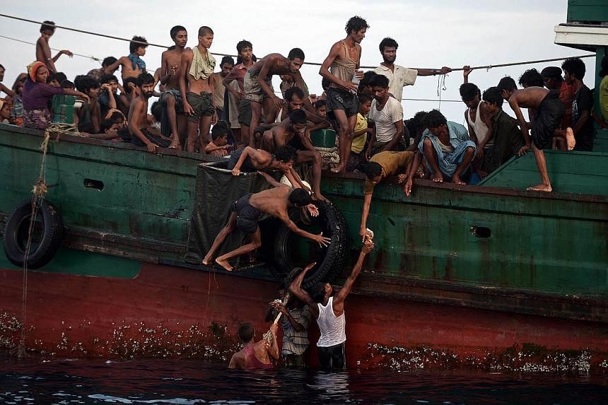 Rohingya migrants passing food supplies dropped by a Thai army helicopter to others aboard a boat off the southern island of Koh Lipe yesterday. The boat was found drifting in Thai waters, with passengers saying several people had died over the last 