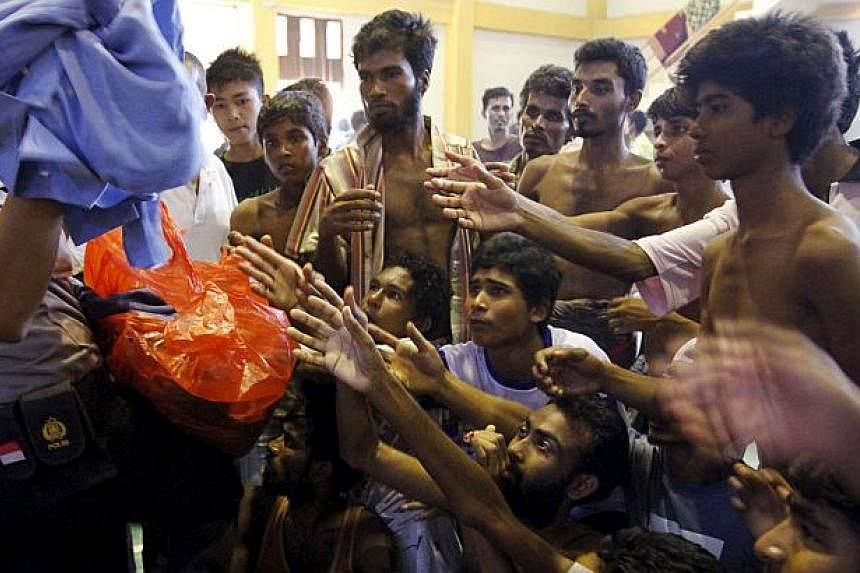 An Indonesia policeman distributes used clothes to migrants believed to be Rohingya inside a shelter in Lhoksukon, in Indonesia's Aceh province on May 11, 2015. -- PHOTO: REUTERS