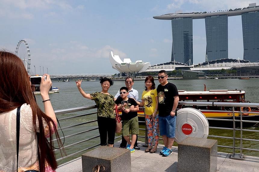 A lady taking a group photograph for tourists from China at the Merlion. It will be less of a hassle for some travellers from China to visit Singapore from June 1. -- ST PHOTO: LIM SIN THAI&nbsp;