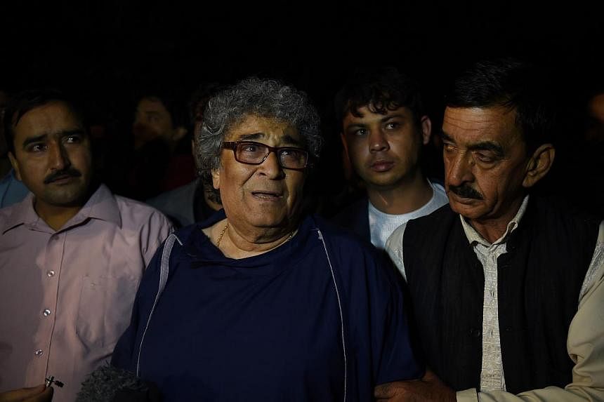 Afghan classical singer Altaf Hussain (centre) who was due to host a concert walks after being rescued by security forces at the Park Place guesthouse in Kabul on May 14, 2015.&nbsp;Fourteen people, most of them foreigners, were killed in a Taleban a