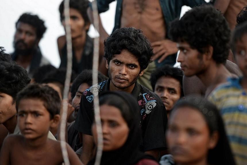 Rohingya migrants sitting in a boat drifting in Thai waters off the southern island of Koh Lipe in the Andaman. Trafficking experts say Thailand is the centre of a multi-million-dollar trade run by competing transnational criminal syndicates. -- PHOT