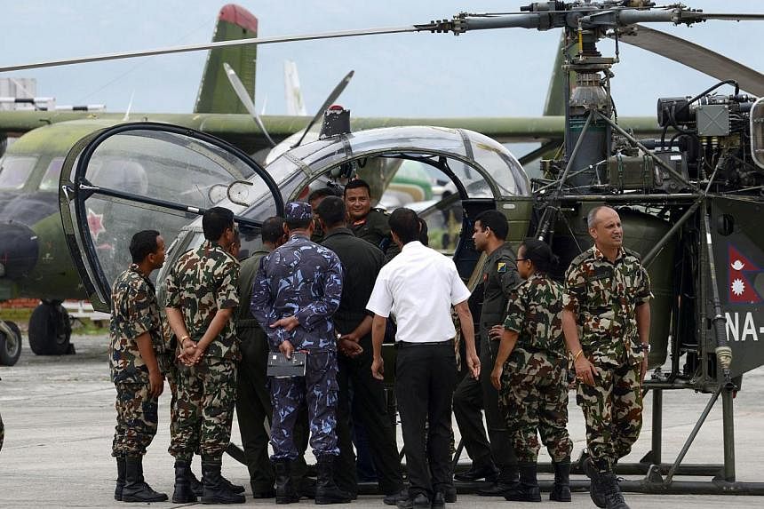 Nepalese army personel gathering in front of a helicopter, whose crew spotted the wreckage of a US Marine helicopter, at the army air base in Kathmandu on May 15, 2015 -- PHOTO: AFP