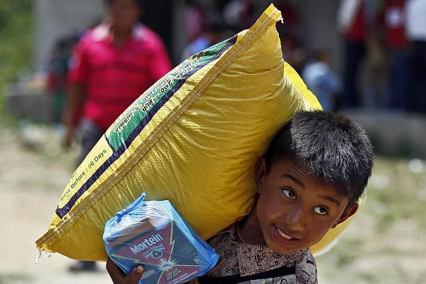 A Nepalese earthquake survivor carries a sack of rice during a food distribution in Jaharsingh Pauwa, Nepal on May 16, 2015. -- PHOTO: EPA