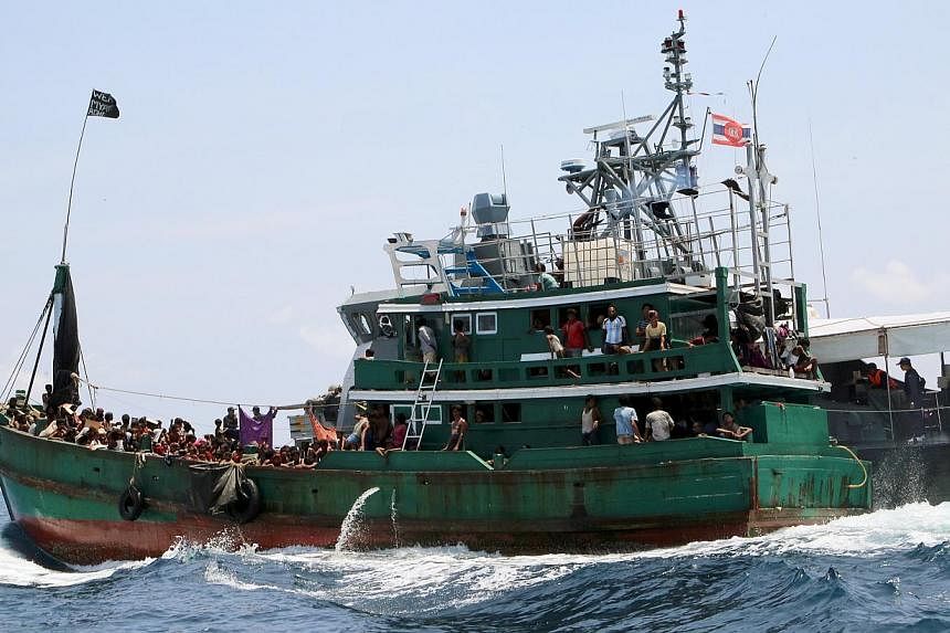 A boat with migrants is being towed away from Thailand by a Thai navy vessel, in waters near Koh Lipe island on May 16, 2015. -- PHOTO: REUTERS